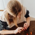 Girl playing with wooden blocks at home, enjoying creative playtime. Captured in high-angle view indoors.